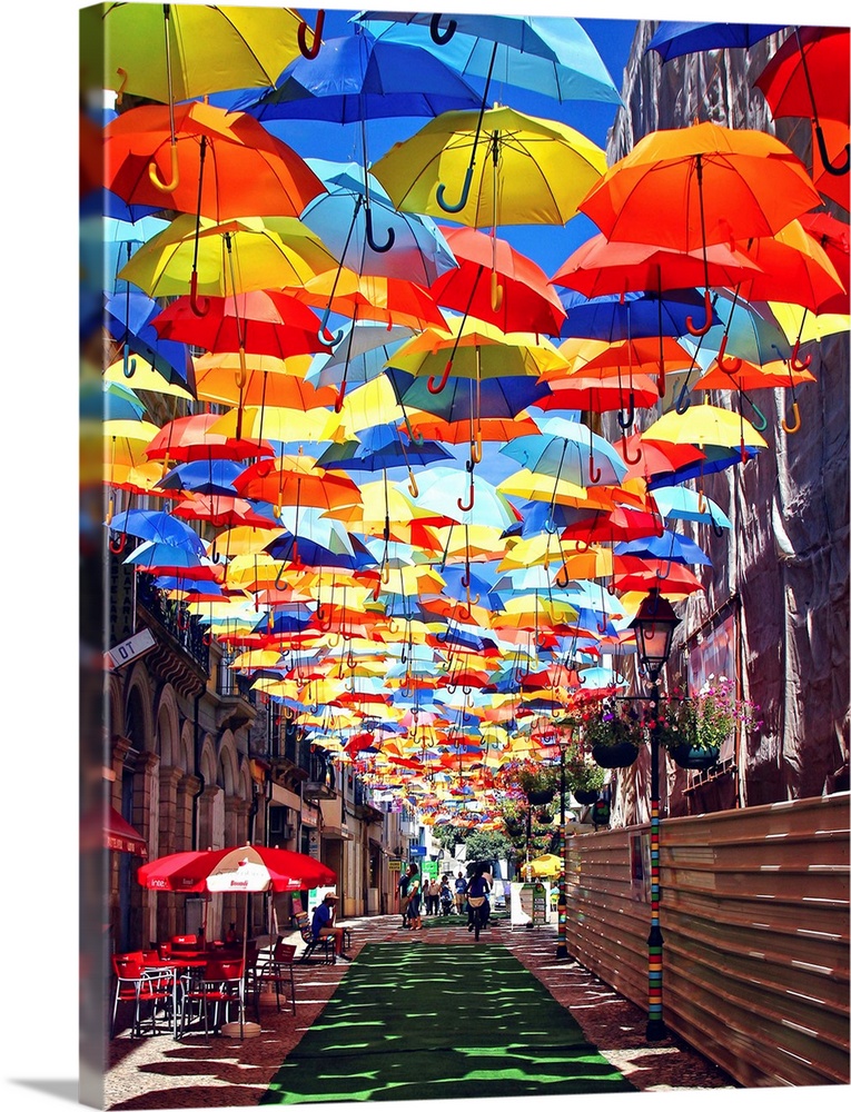 Colorful umbrellas hanging over a walkway creating a shady path inAgueda, Portugal.