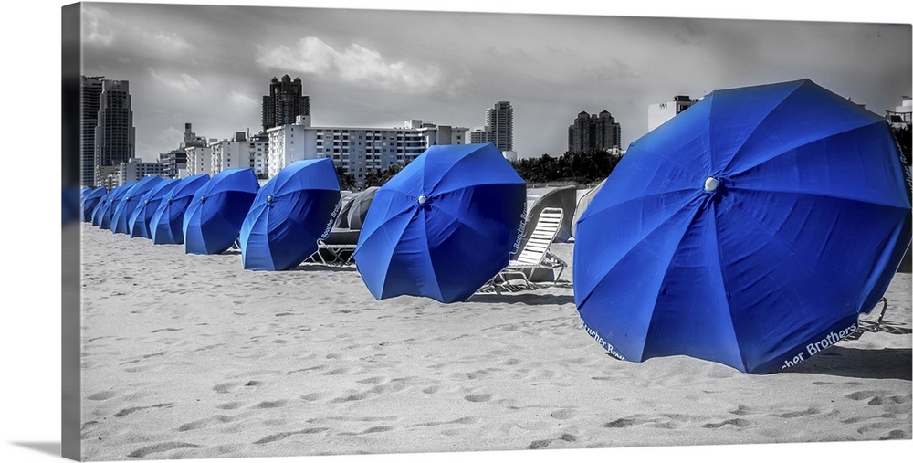 Blue beach umbrellas in the sand at the beach in Miami, Florida.