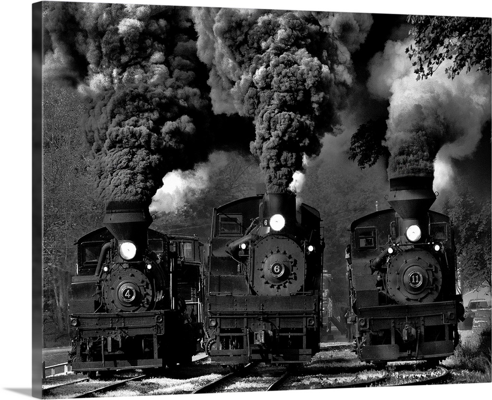 Three locomotives rolling down the tracks with large clouds of smoke coming from their smokestacks.