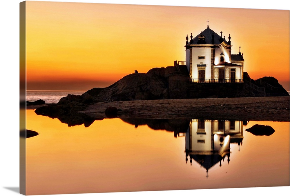 A chapel on an island at sunset, with a mirror reflection in the water below.