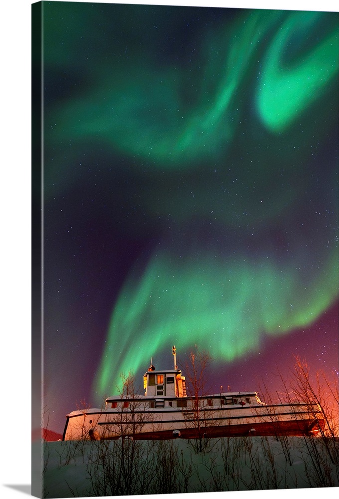 Old steamboat under a sky full of dancing northern lights. Located in Dawson City, Yukon, Canada