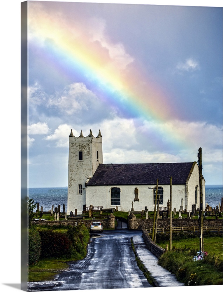Photograph of Ballintoy Parish Church with a beautiful rainbow behind it over the ocean, at Ballintoy Harbour near Bushmil...