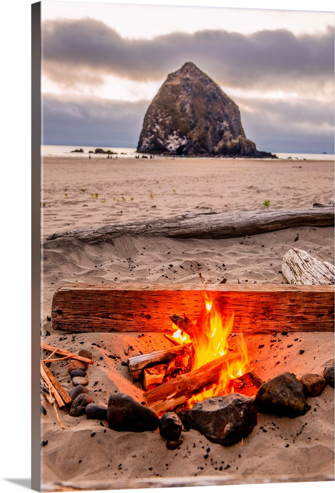 Photograph of a fire on the beach with Haystack Rock in the background at Cannon Beach, Oregon.