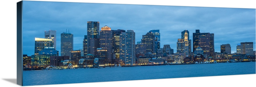 Panoramic view of the Boston City skyline at night, with a cloudy sky overhead.