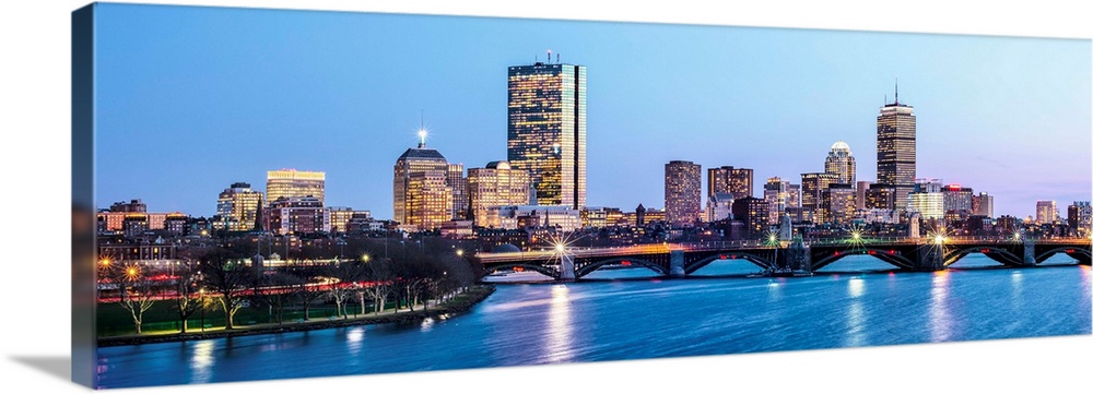 Panoramic view of the Boston City skyline illuminated at night, with the Longfellow Bridge in the foreground.