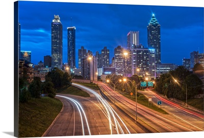Busy freeway with light trails, with the Atlanta, Georgia skyline in the distance