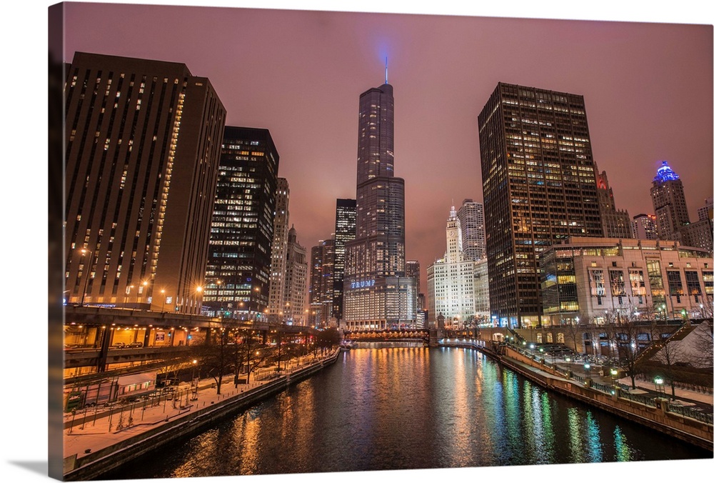 Photo of tall buildings in the city of Chicago illuminated at dusk and reflected in the Chicago River.