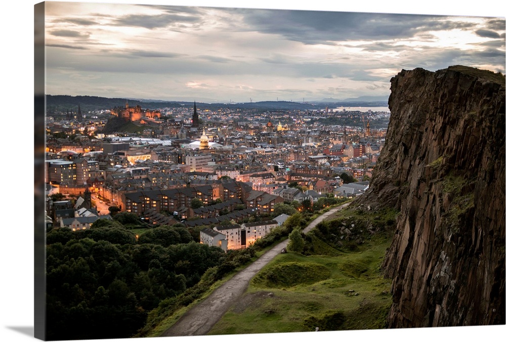 Photograph of the city of Edinburgh, Scotland lit up at sunset with a view from Holyrood Park.