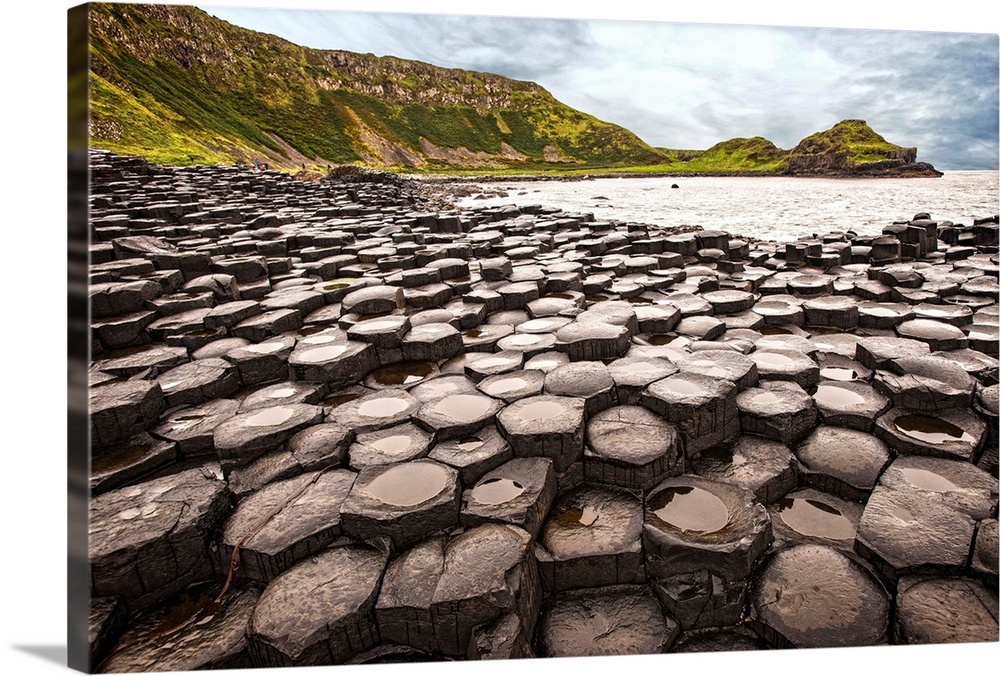 Landscape photograph of the basalt columns on Giant's Causeway with rocky cliffs and the Atlantic Ocean in the background.