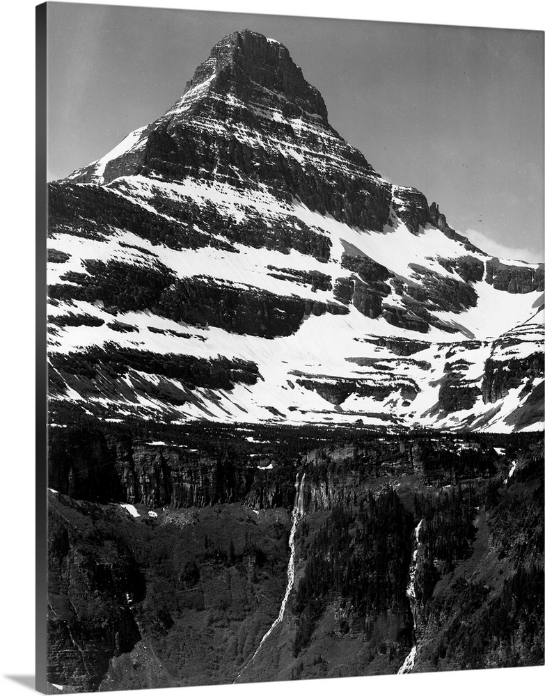 In Glacier National Park, vertical, full view of snow covered mountain, including area below timberline.