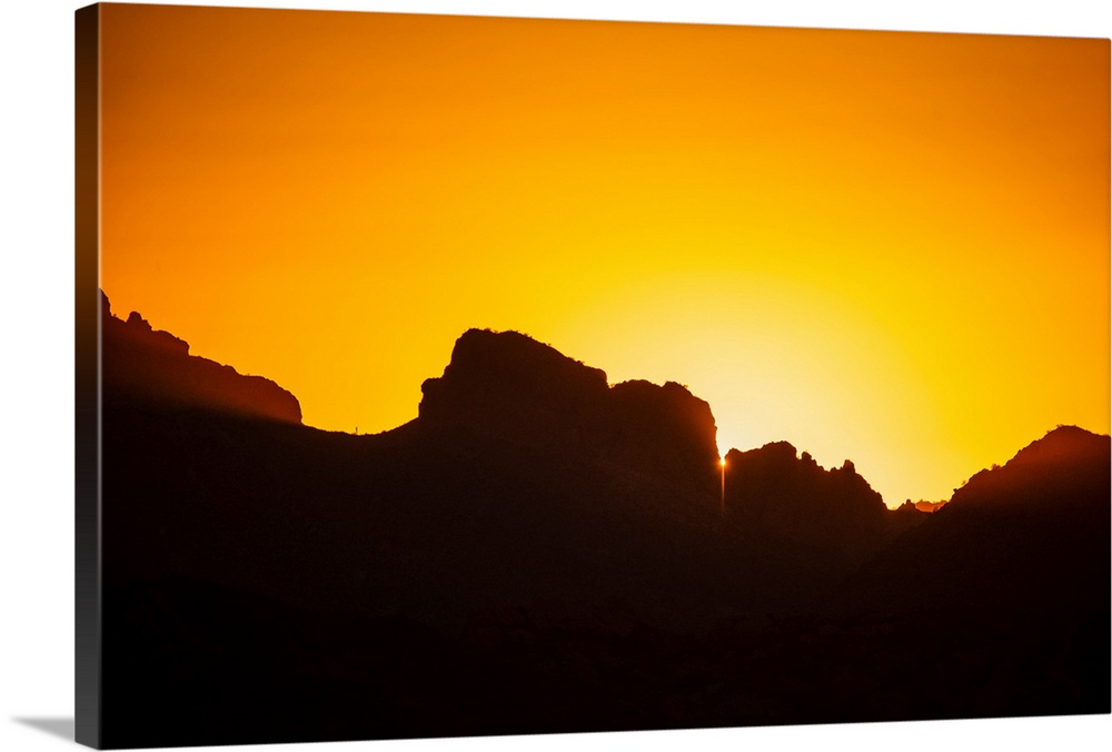 Photo of a golden sunset over silhouetted rocks in Phoenix, Arizona.