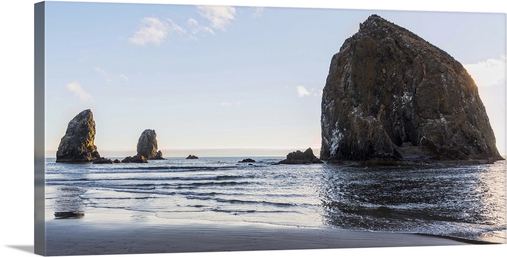 Panoramic photograph of Haystack Rock at Cannon Beach with blue skies.