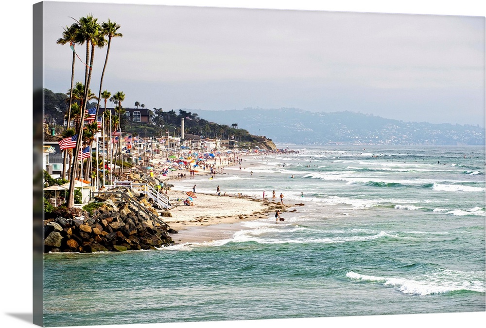 Landscape photograph of the La Jolla coast filled with beach goers and palm trees.