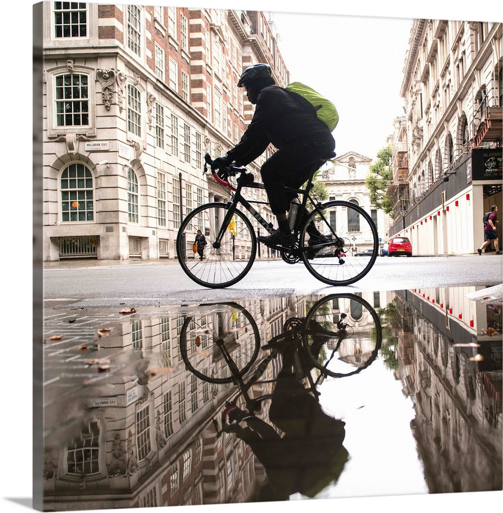 Square photograph of a biker reflecting into a puddle in London, England.