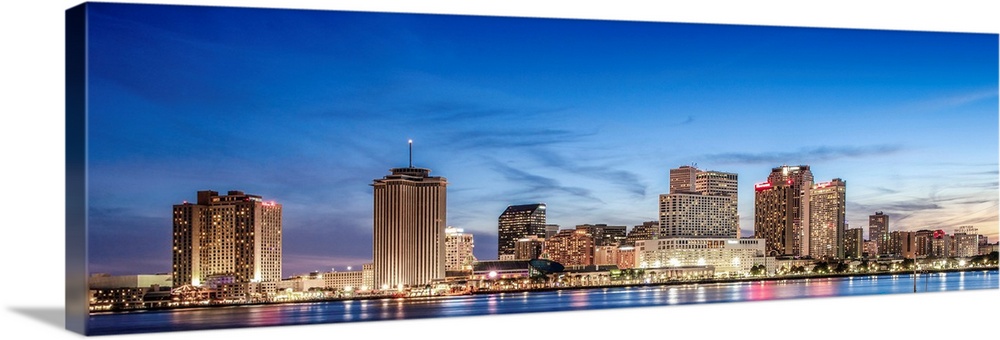 Panoramic photograph of the New Orleans skyline lit up at sunset.