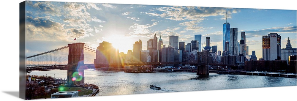View of the New York City skyline as the sun setting with the Brooklyn Bridge, from across the water.