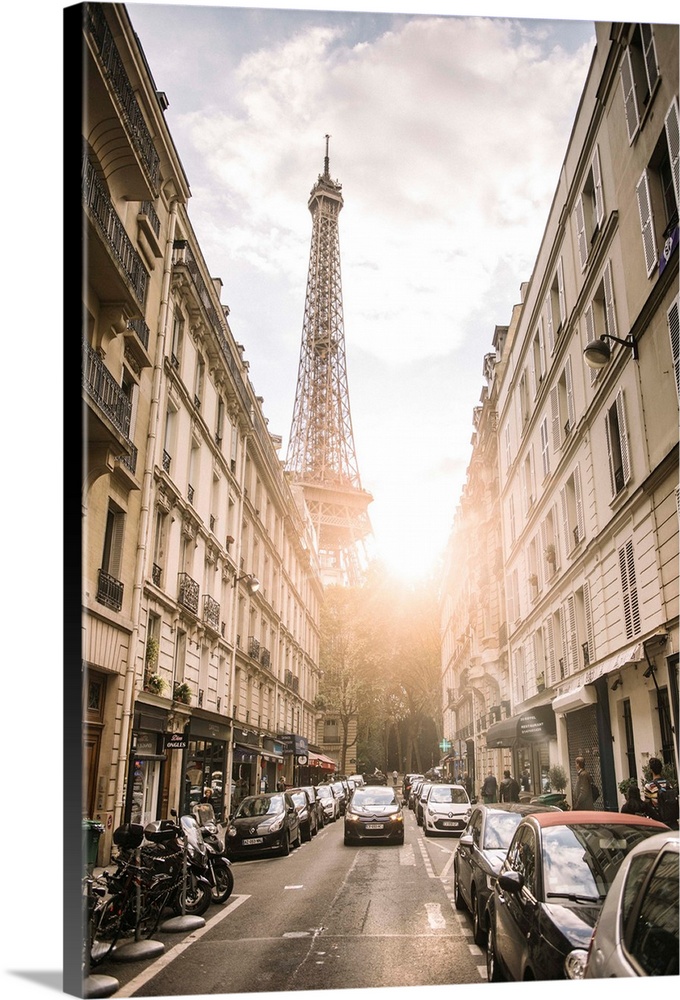 Photograph of a streetscape in Paris with the sun beaming through the Eiffel Tower in the background.