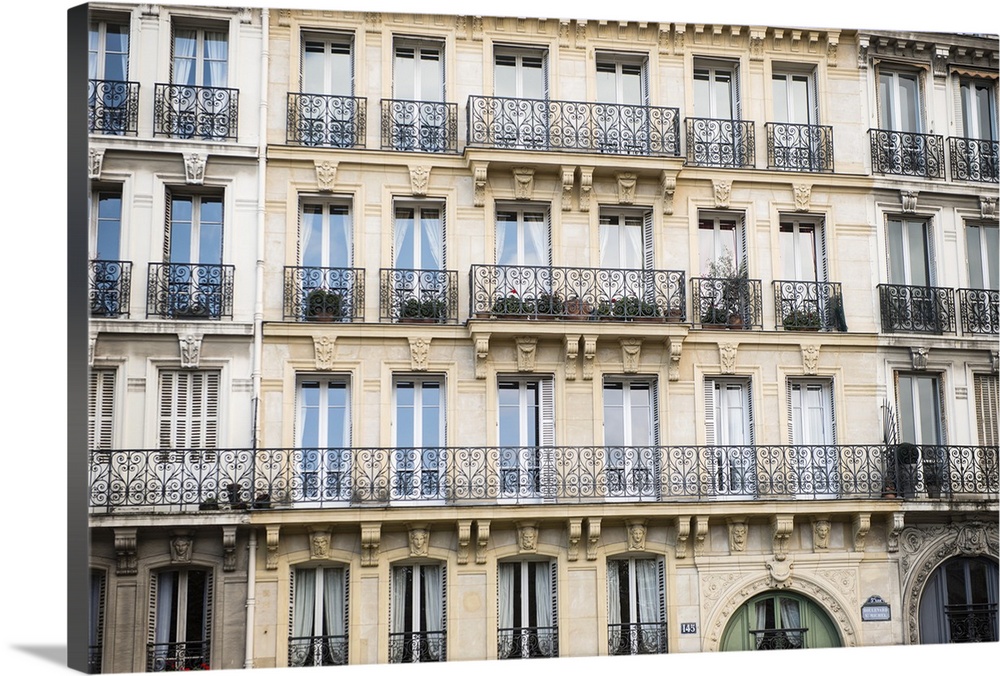 Photograph of a Parisian building with rows of windows and unique railings.