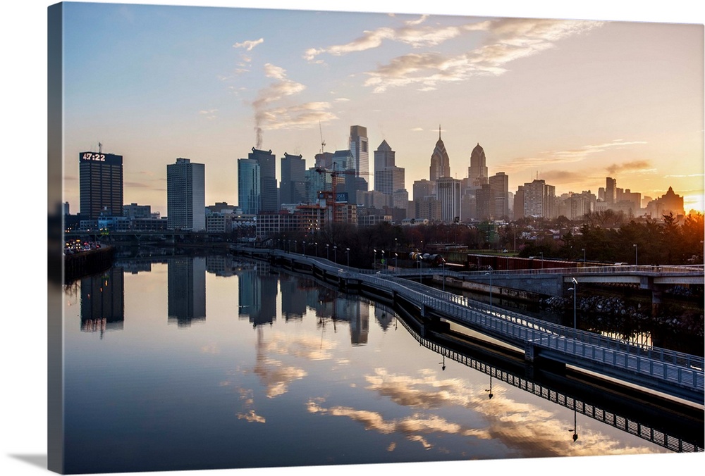 The sun rises above Philadelphia's city skyline with the sky reflecting on the Delaware river.