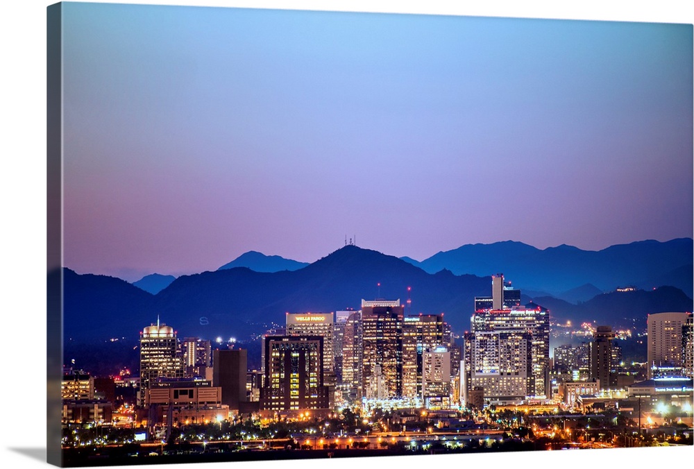 Photograph of a colorful sunset over the Phoenix, Arizona skyline with silhouetted mountains in the background.