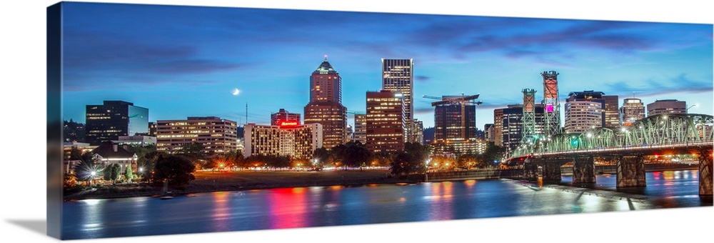 Panoramic photograph of a saturated Portland, Oregon skyline at sunset reflecting onto the Willamette River with a moon in...