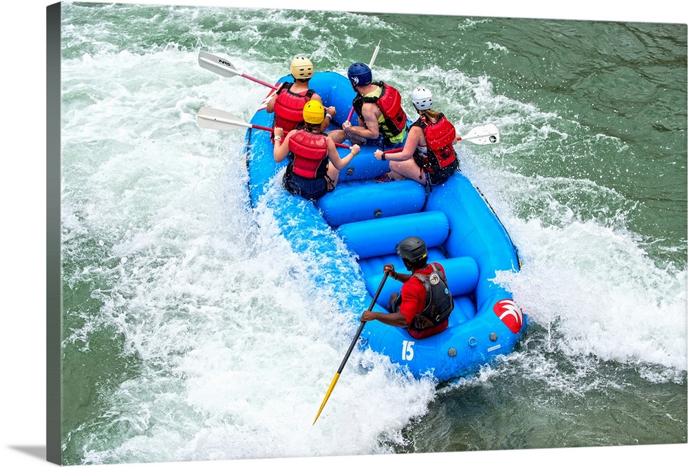 A raft filled with people float in whitewater rapids.
