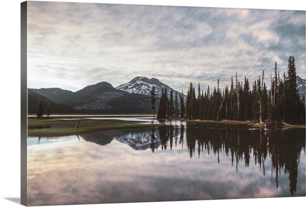 View of trees reflecting in Sparks Lake on a cloudy day in Deschutes National Forest, Oregon.