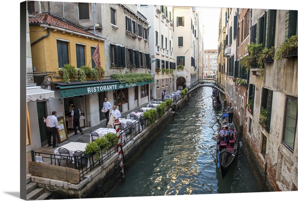 Photograph of a canal in Venice with gondolas in a row, rowing by Ristorante Da Raffaele.