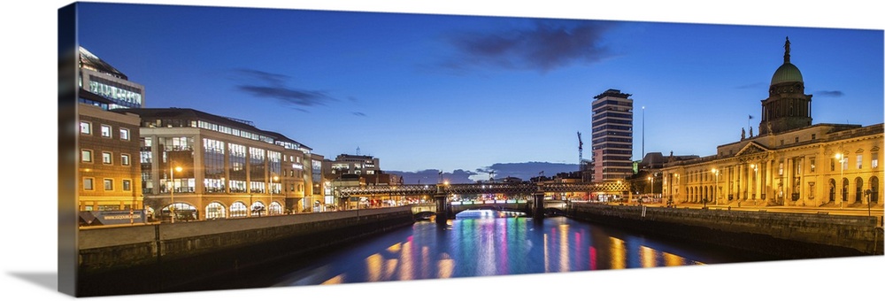 Panoramic photograph going straight down the River Liffey with buildings, highlighting The Custom House, on the sides lit ...