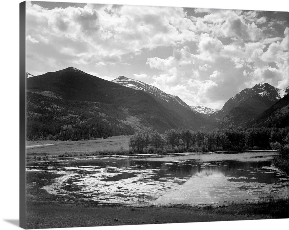 In Rocky Mountain National Park, lake and trees in foreground, mountains and clouds in background.
