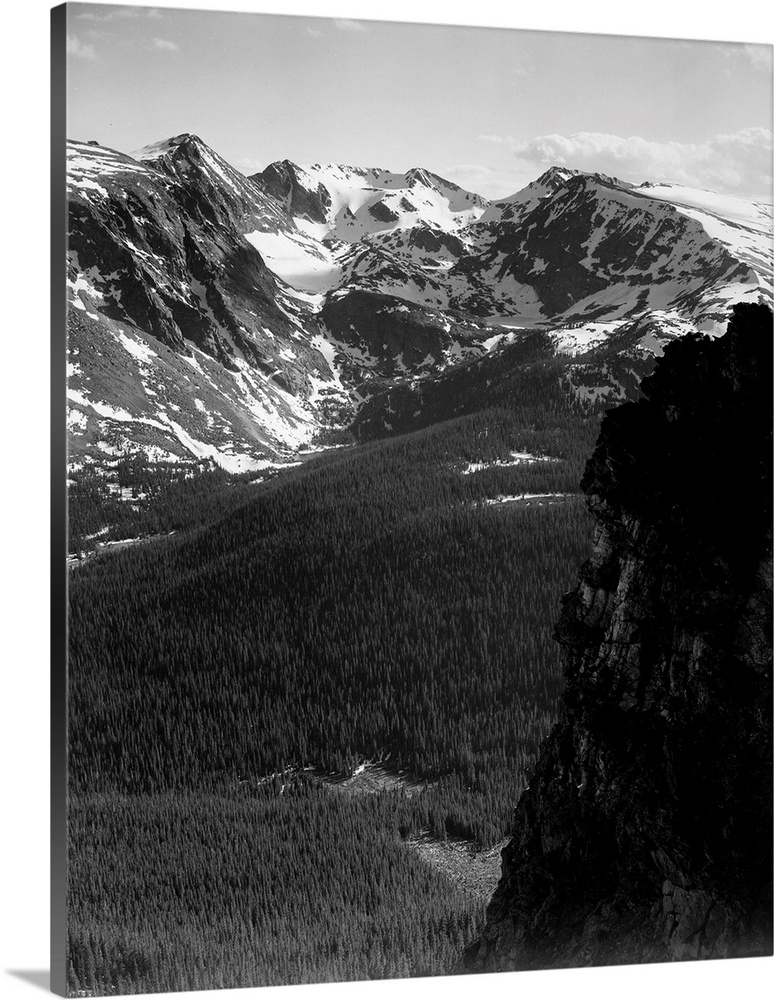 In Rocky Mountain National Park, vertical panorama of snow-capped mountain timbered area below.