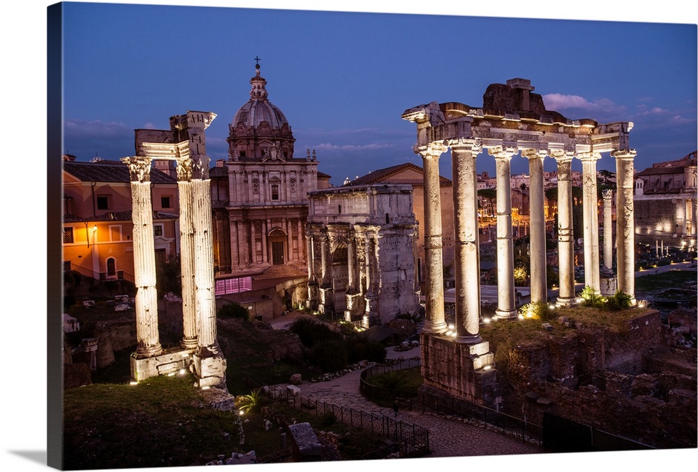 Photograph of the ruins at the Roman Forum lit up at night.