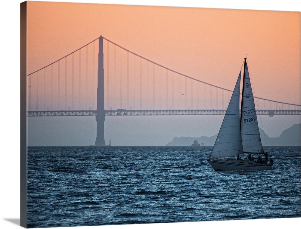 Sunset photograph of a sailboat on the San Francisco Bay with the Golden Gate Bridge in the background.