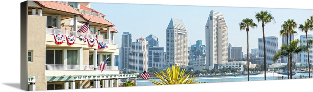 Panoramic photograph of part of the San Diego, California skyline with flowers, palm trees, and American flags in the fore...