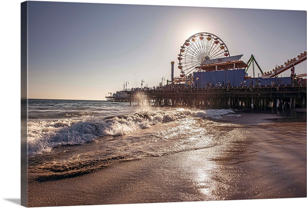 Photograph of the Santa Monica Pier in Los Angeles, California, with the sun setting right behind the Ferris Wheel.