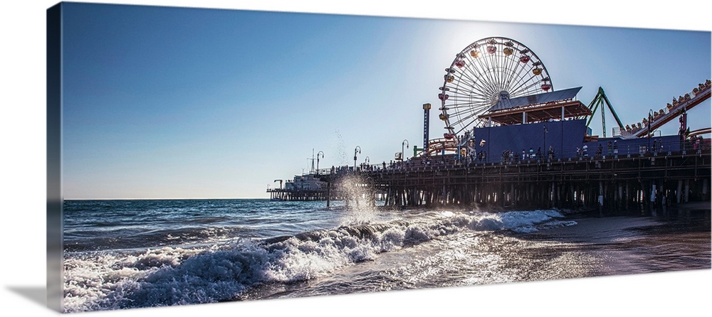 Panoramic photograph of the Santa Monica Pier in Los Angeles, California, with the sun setting right behind the Ferris Wheel.