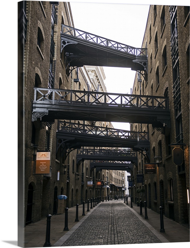 Photograph of Shad Thames lined with warehouses and walkways alongside Tower Bridge in London.