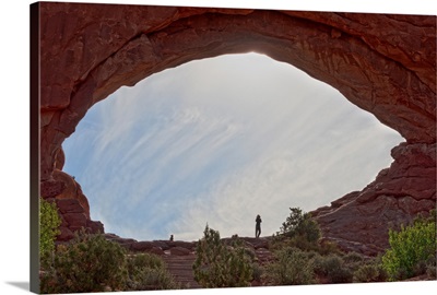 Silhouette of a person framed by the Wilson Arch, Arches National Park, Utah