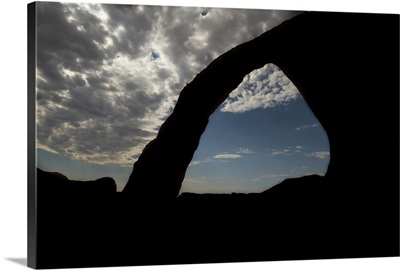 Silhouette of Corona Arch under cloudy skies, Arches National Park, Utah