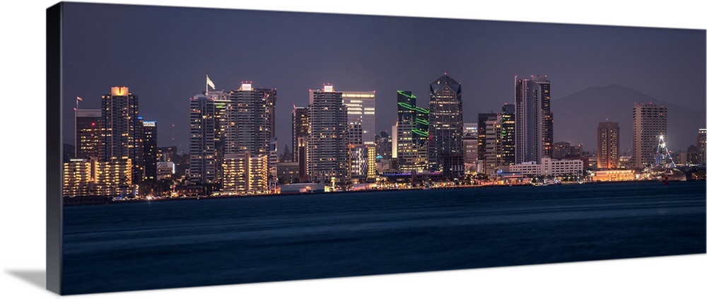 Panoramic photograph of the San Diego, California skyline lit up at night from across the water.