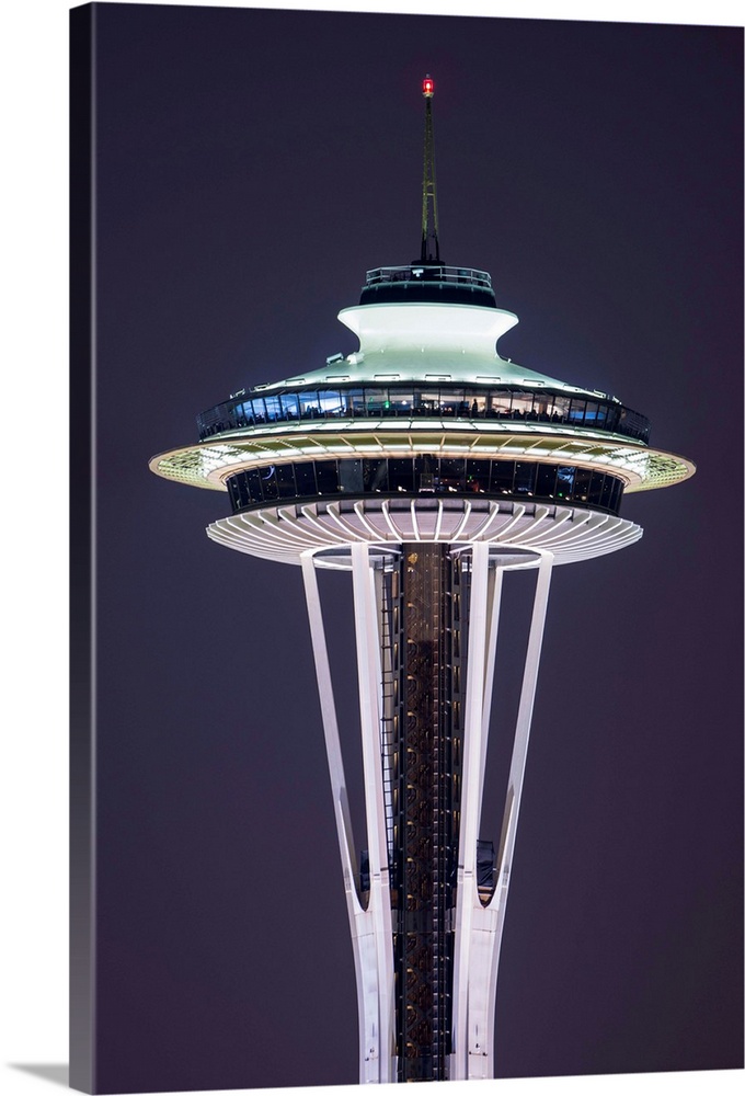 Photograph of the Seattle Space Needle lit up at night with dark purple skies in the background.