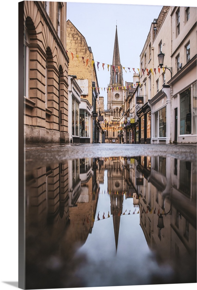 Photograph of St. Michael's Church reflecting into a puddle in the middle of a street in Bath, England.
