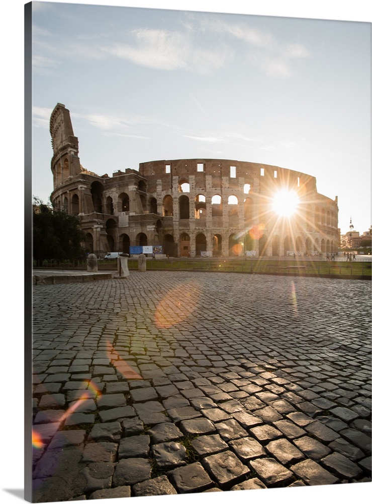 Photograph of the sun shining right though the middle of the Colosseum.