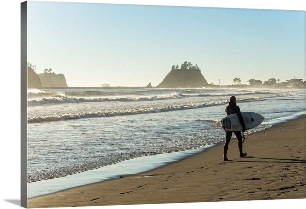 Photograph of a surfer walking along the shore at La Push Beach in Washington.