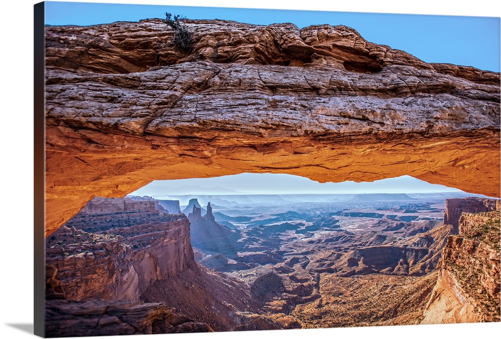The underside of the Mesa Arch glowing bright orange with sunlight, with Buck Canyon in the distance, Canyonlands National...
