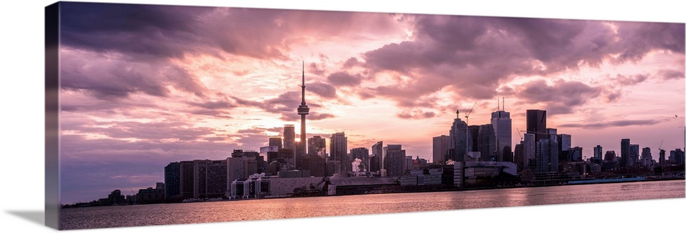 Toronto city skyline under a dramatic sunset with clouds overhead, Ontario, Canada.