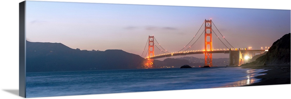 Panoramic photograph at twilight of the Golden Gate Bridge taken from the shore.