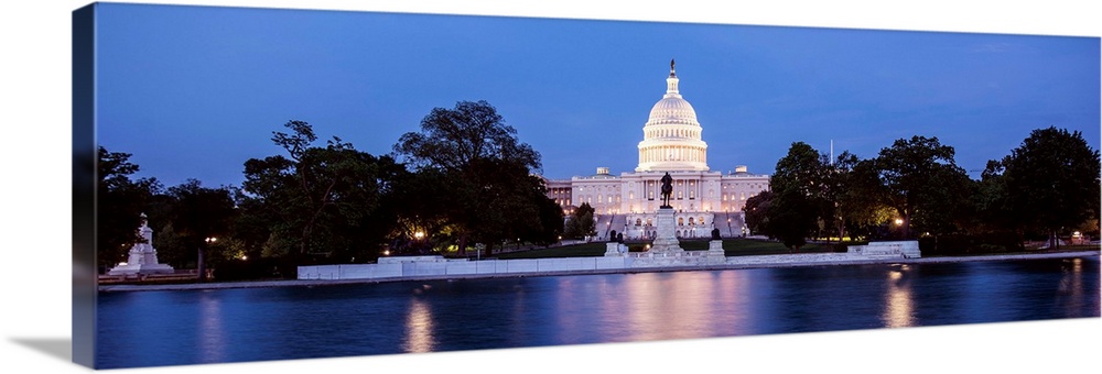 Panoramic photograph of the U.S. Capitol Building at dusk with blue and magenta hues from the Capitol Reflecting Pool.