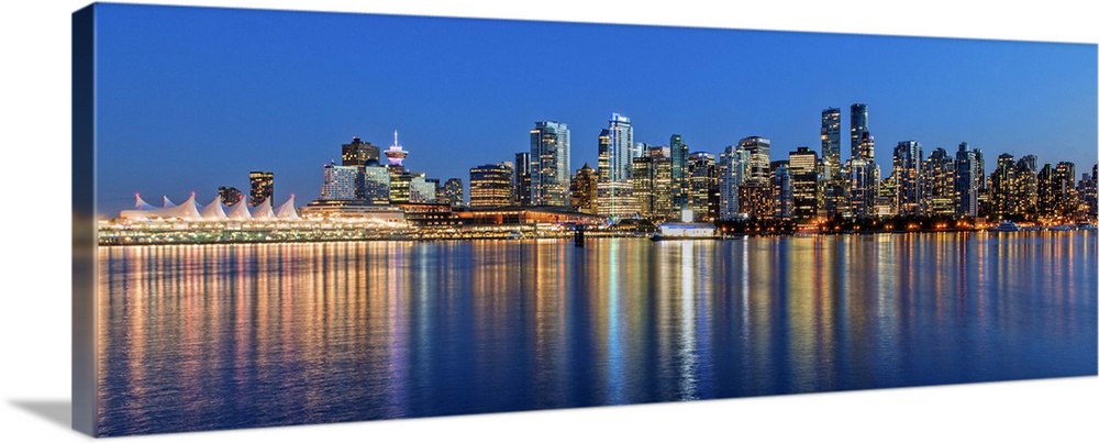 Photograph of the downtown Vancouver skyline lit up at dusk and reflecting onto the water creating bands of color, Vancouv...