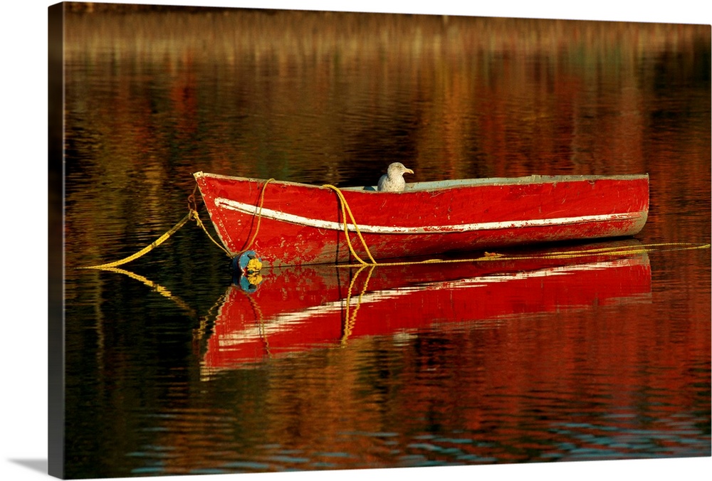 A moored old red boat and its mirror reflection on still waters.